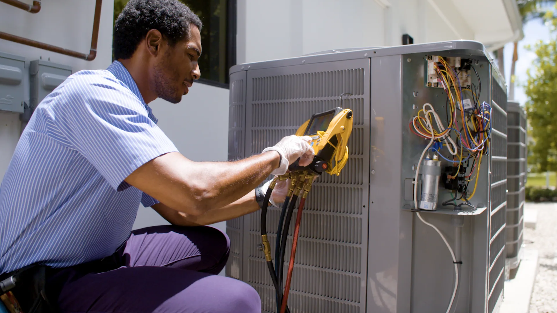 An HVAC technician servicing an air conditioning condenser during the filming of a Cousins Air TV commercial produced by Full Moon Creative in South Florida
