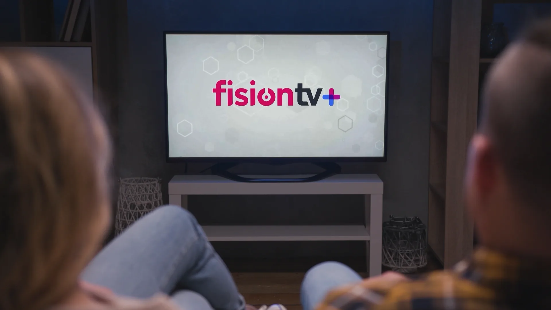 A couple on a couch watching a Hotwire Fision TV+ commercial produced by Full Moon Creative play on their living room television