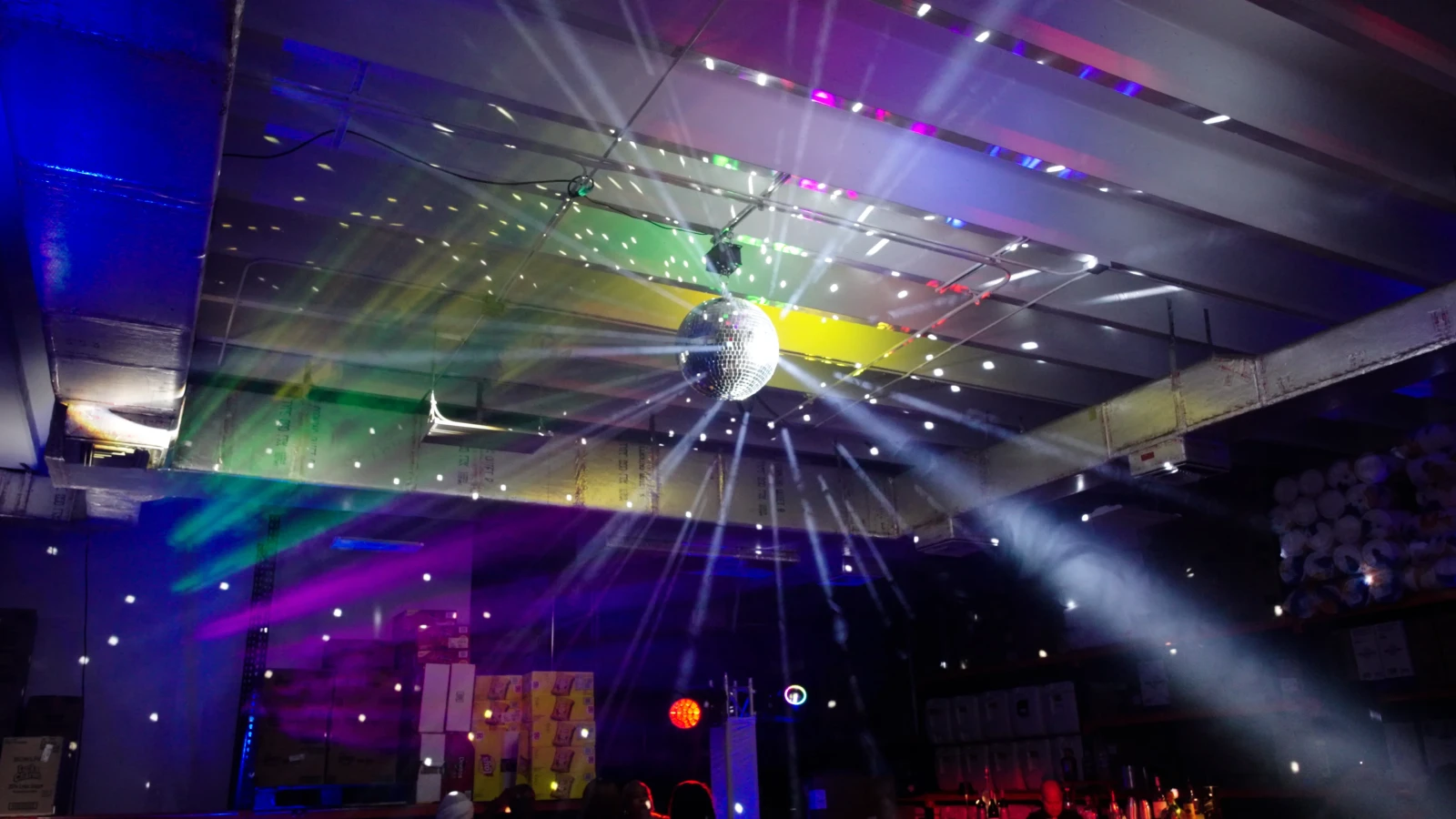 A mirror ball and colorful stage lighting throwing beams across a South Florida event venue, rigged and run by one production and AV team